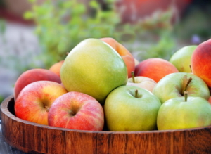 green and red apples in wooden tray outdoor